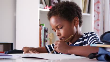 Young-Boy-Sitting-At-Desk-In-Bedroom-And-Drawing