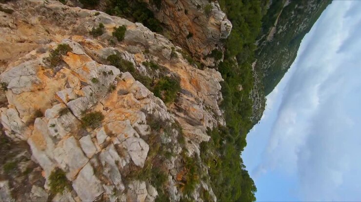 Stunning aerial drone view speeding down a rocky cliff toward the ocean on the Mediterranean coast of Spain