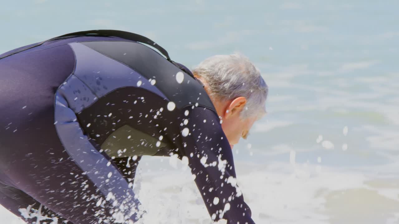 vista trasera de un surfista masculino caucásico senior activo jugando con las olas del mar en la playa 4k