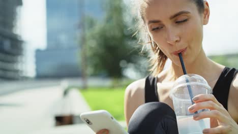 video of young woman drinking and using mobile phone outdoors