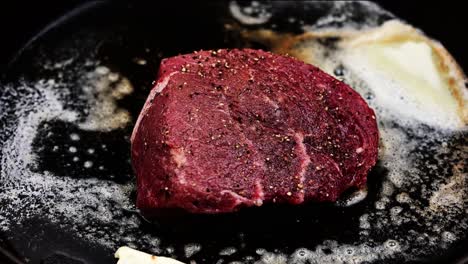 raw steak cooking in butter on cast iron skillet