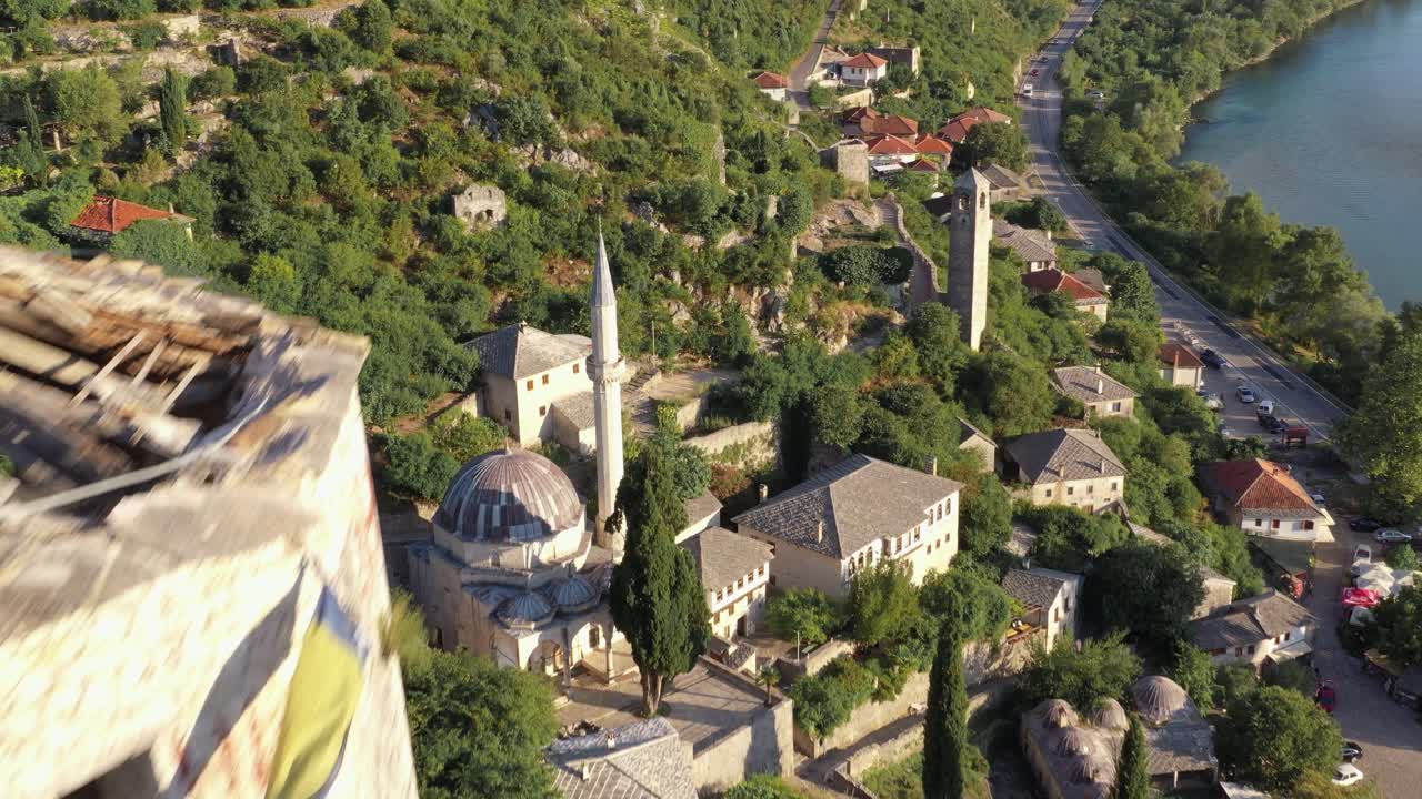 Drone flight over village at a river and castle tower with broken roof at foot of a mountain