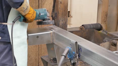 close-up view of a worker using an angle grinder on a metal structure in a factory
