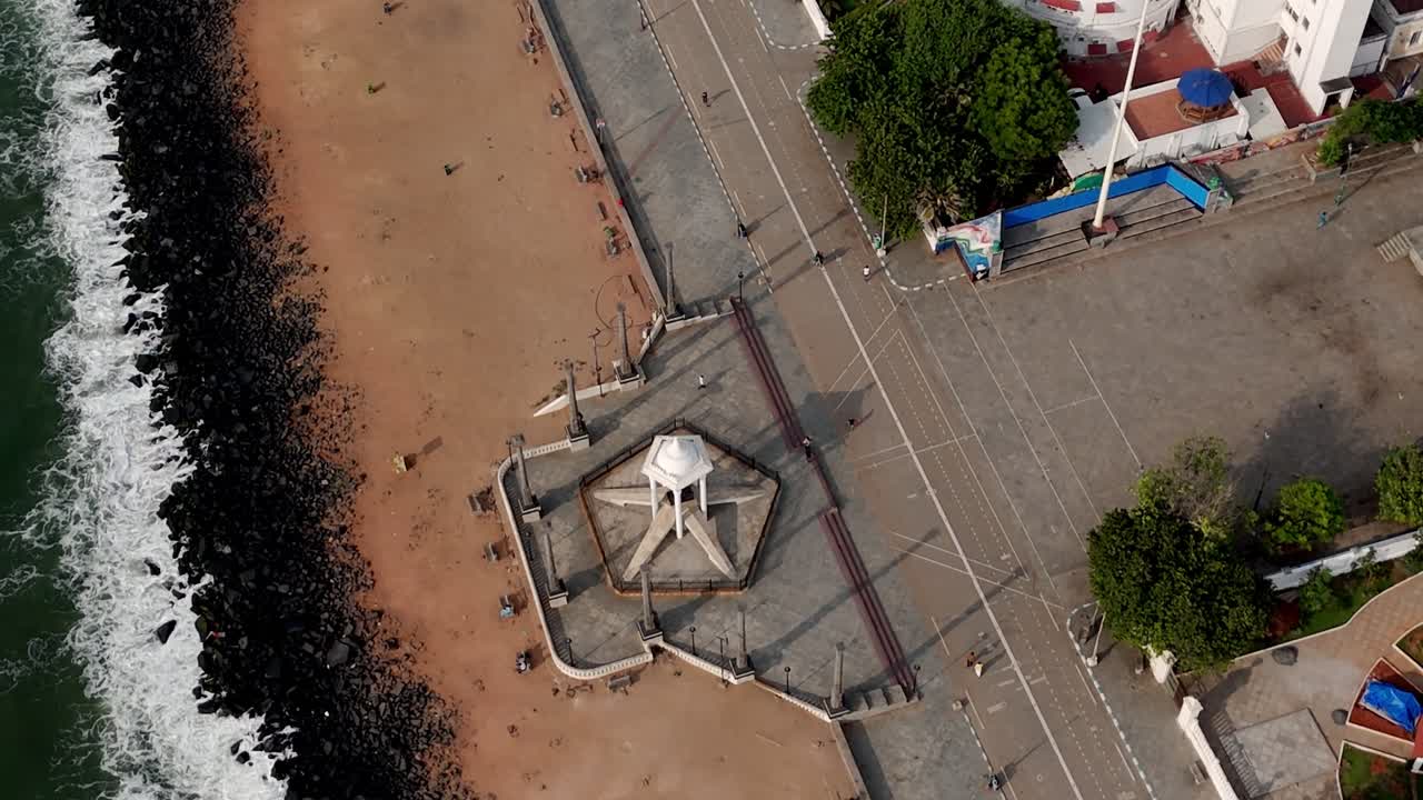 This early morning aerial video the city's upscale areas and Rock Beach, with gentle waves crashing near the iconic Mahatma Gandhi statue and a prominent lighthouse standing as a city landmark