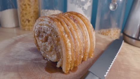 slider shot of breaking a roast pork belly joint on a cutting board in the kitchen