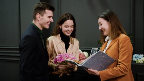mujer asiática mostrando un libro de muestra a una pareja