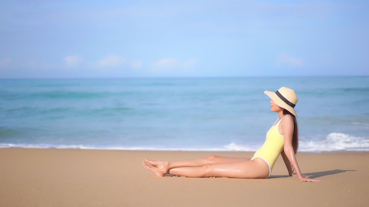 Profile of a young sexy woman sunbathing on a sandy beach as the title rolls in