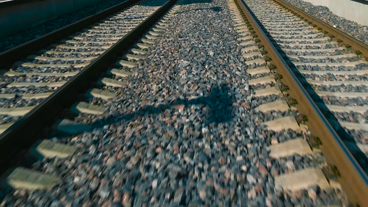 Low angle forward motion along railroad, between two straight train tracks. Pov train ride and railway perspective. Flight over railway line and vibrant gravel ground. rail road tracks side by side