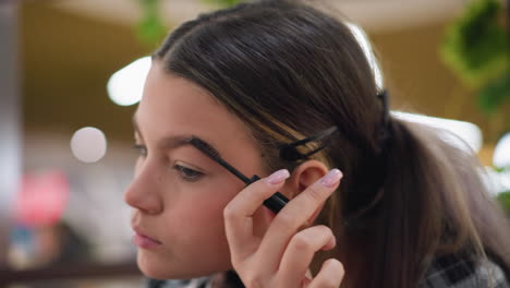 toma de primer plano de una dama tallando suavemente sus cejas con un pincel de cejas, fondo de enfoque suave que muestra el entorno de belleza, haciendo hincapié en la precisión en el aseo y la mejora de las cejas