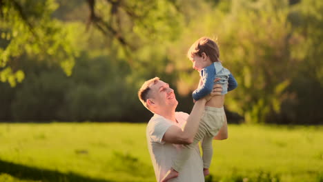 Papas-Hände-Halten-Einen-Kleinen,-Glücklich-Lächelnden,-Süßen-Sohn,-Der-Zusammen-In-Der-Natur-Spielt,-Auf-Dem-Land,-POV-Aufnahme,-Unbeschwerte-Familie,-Die-Das-Wochenende-Genießt,-Entspannt-Und-Eine-Schöne-Zeit-Im-Freien-Hat,-Aus-Der-Vogelperspektive.