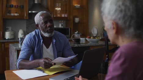 Mixed-race-senior-couple-discussing-and-calculating-finances-at-home