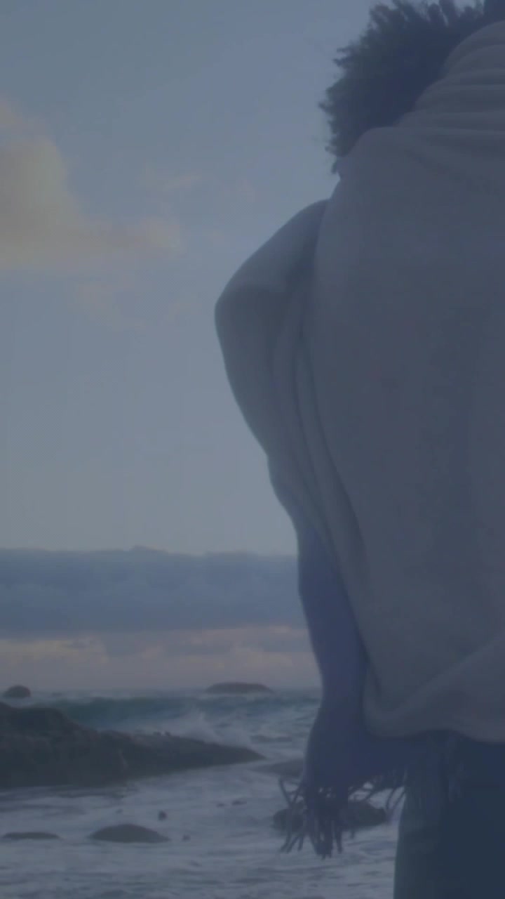 Vertical video: Flare sparking cam pan, couple shore barefoot watching dawn jeans shawl, copy space