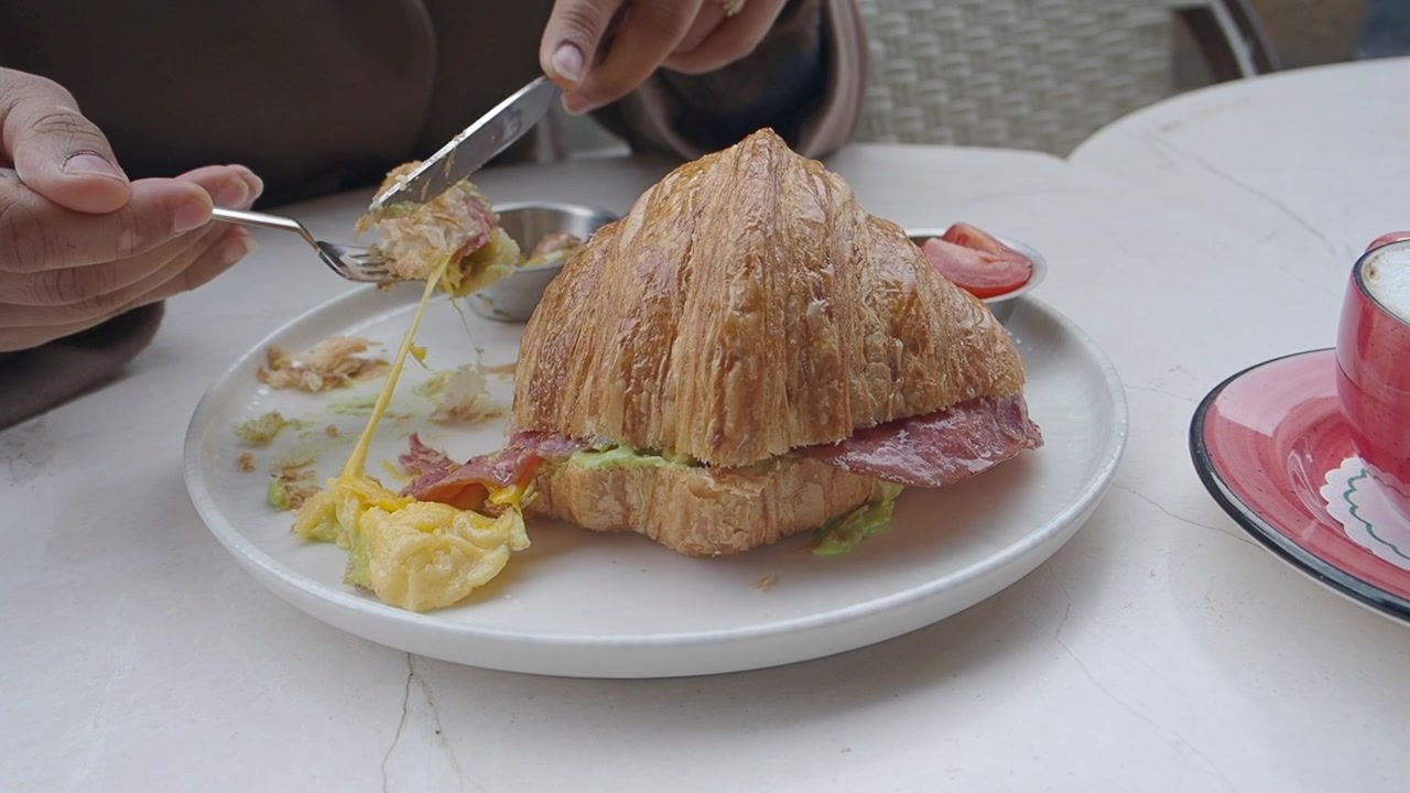 Persona che mangia un cornetto salato in un bar
