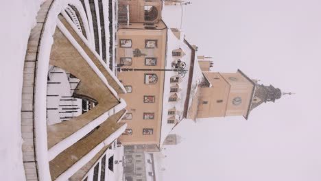 vertical - snow falling in piata sfatului on a winter day in brasov, romania