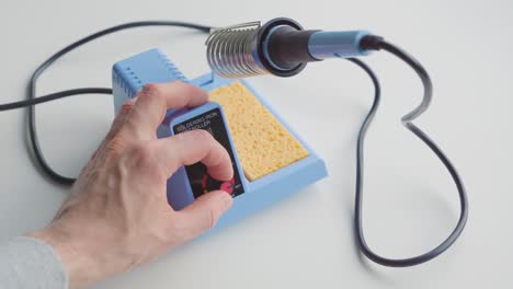 man turning on a soldering iron and adjusting its temperature