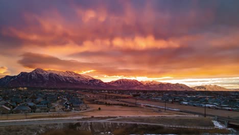 sunrise casts orange rays of sun into the colorful sky and cloudscape above the waking city and highway traffic - aerial hyperlapse