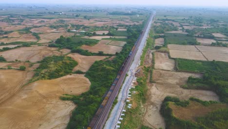 aerial drone shot of a freight train moving through farmlands in morena india