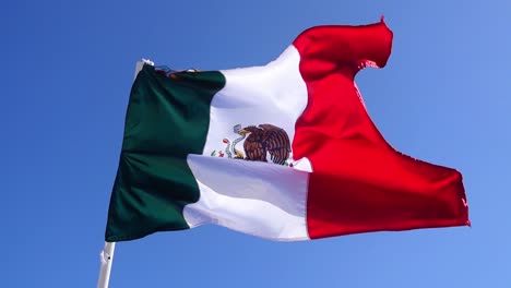 upshot, scenic view of mexican flag, waving on the flagpole in yucatan, mexico, bright blue sky in the background