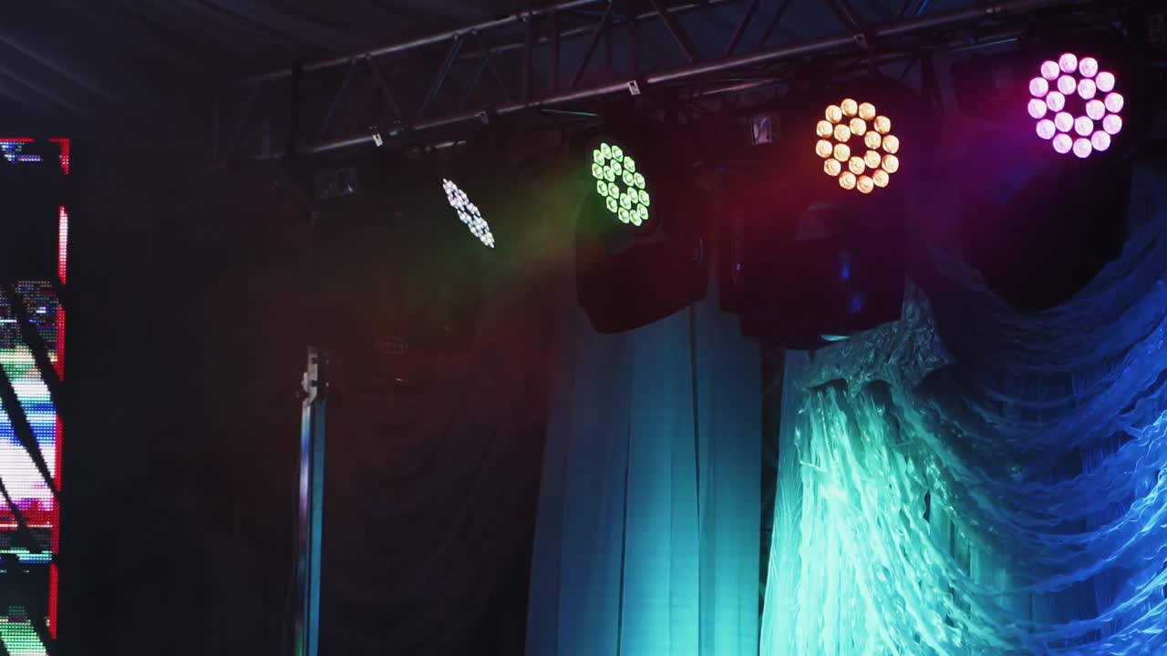 Musical farm on the stage. Bright spotlights turning and shimmering with different colors in the dark night club.