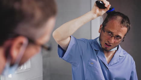 trabajador médico corta el cabello en la cabeza con un cortador eléctrico