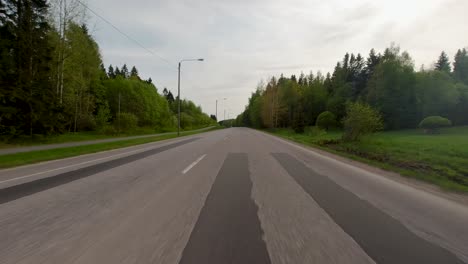 Point-of-view-of-a-car-driving-quickly-along-a-lush-country-road-on-a-sunny-morning