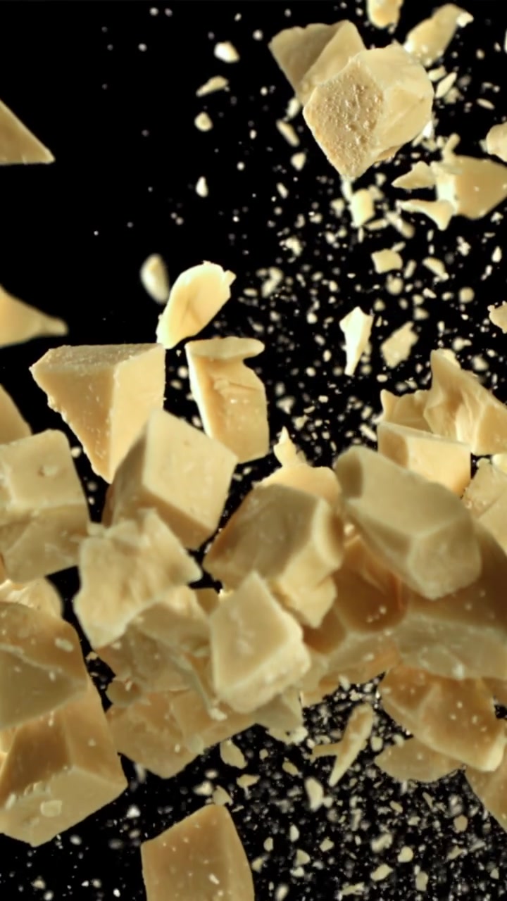 White Chocolate Pieces Falling in Slow Motion on Black Background