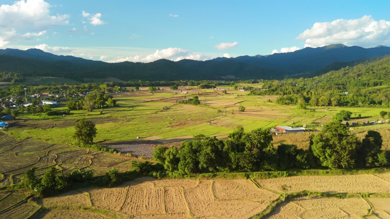 タイ北部ムアンコーンの、収穫後の田んぼと山々に囲まれた美しい小さな山村。遠隔地の農地と農業地帯の空撮。
