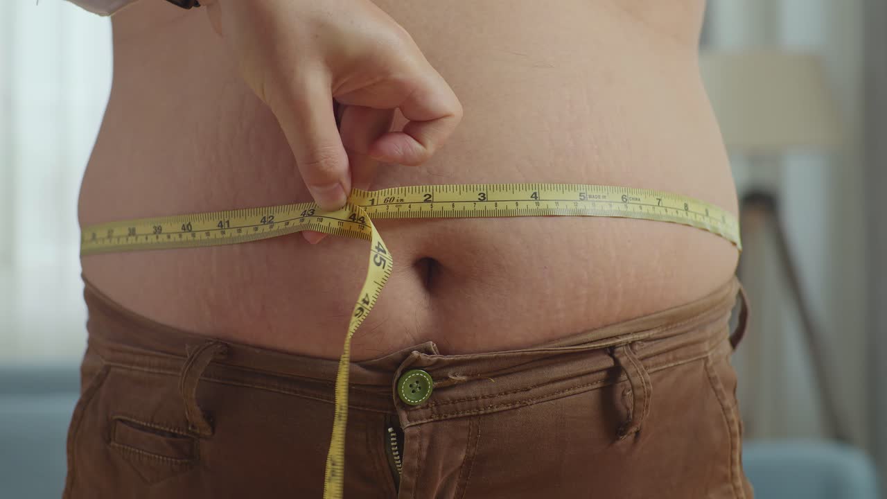 cerca de las manos del médico masculino usando cinta de medición de la cintura del paciente masculino gordo