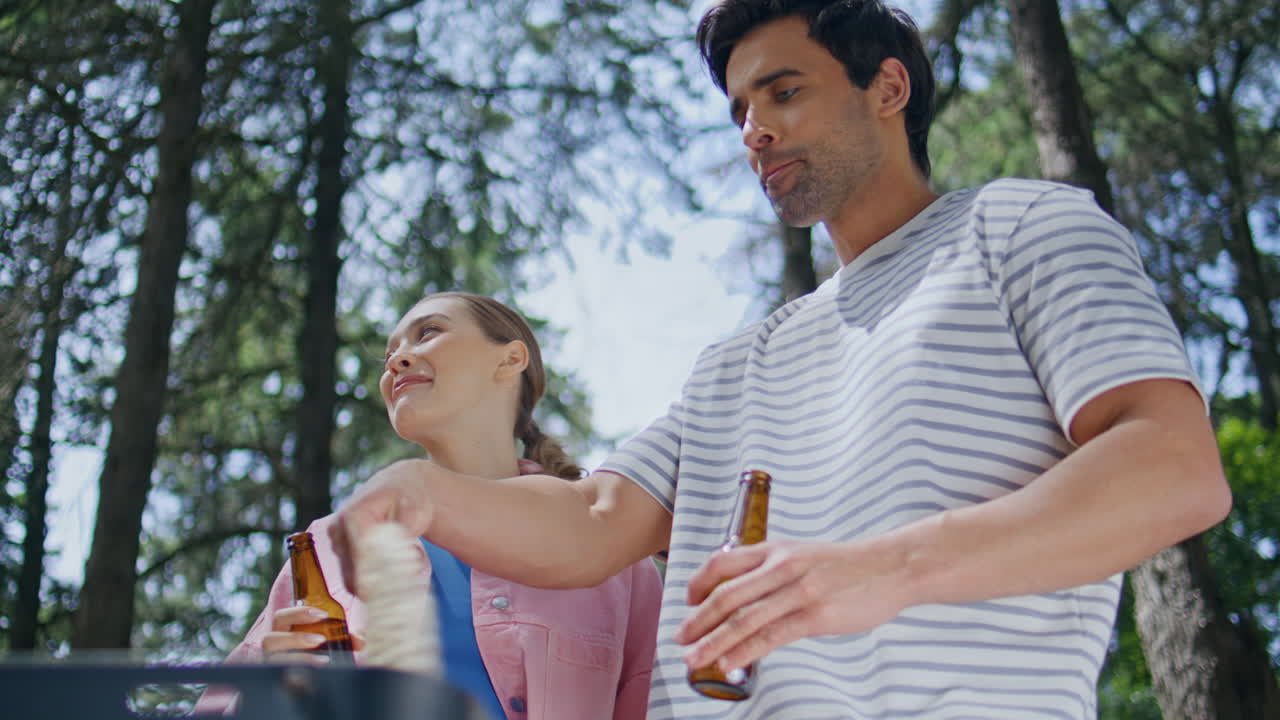 Smiling couple cooking picnic grilling food in forest closeup. Happy woman man