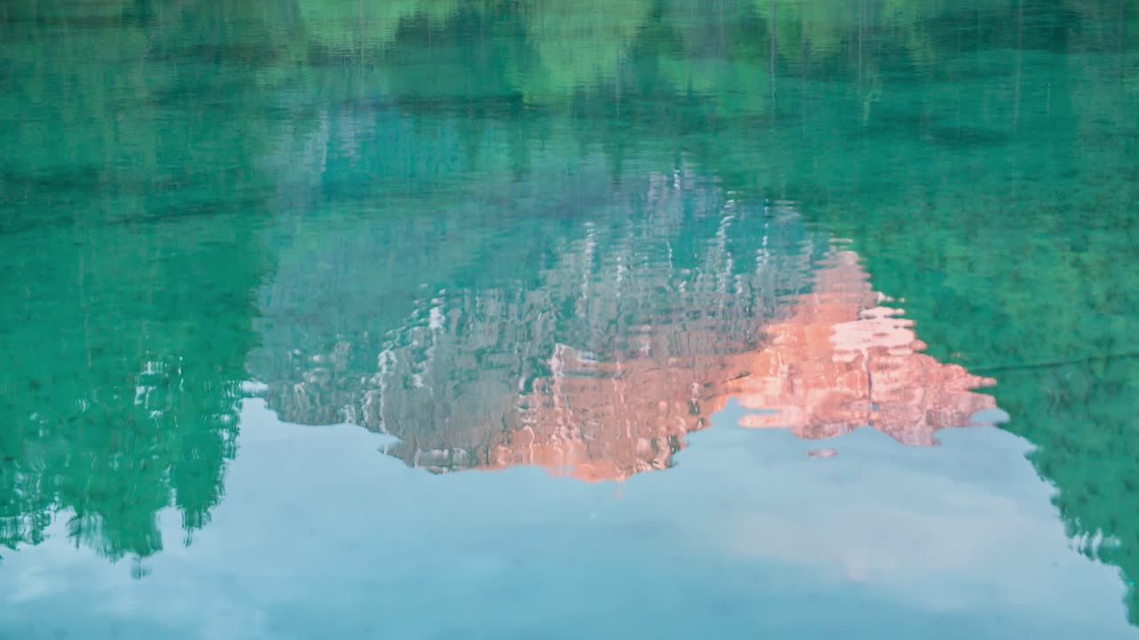 물은 산과 나무가 있는 하늘을 반영합니다.