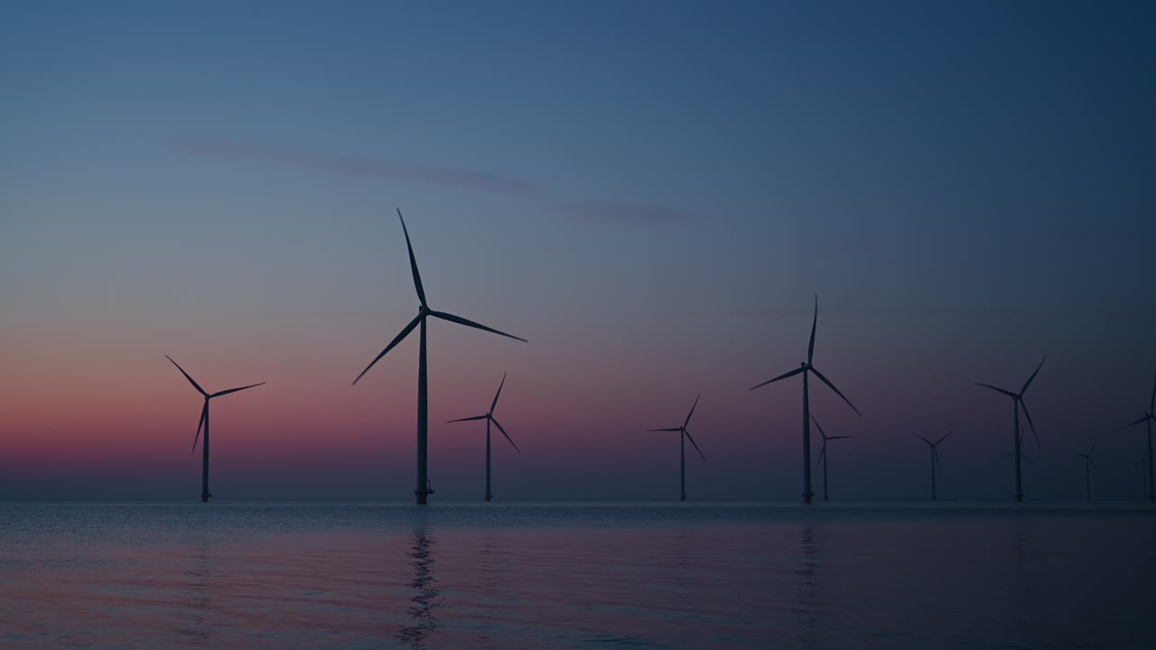 태양이 지는 동안 해상 풍력 공원에서 지속 가능한 재생 가능한 에너지를 생산하는 풍력 터빈.