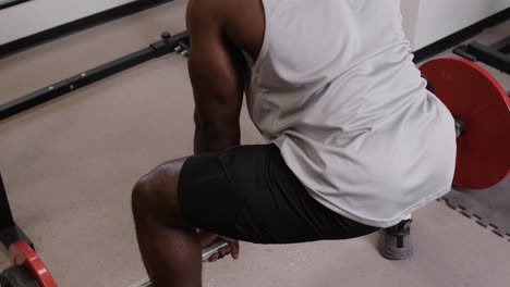 man performing barbell squats in gym