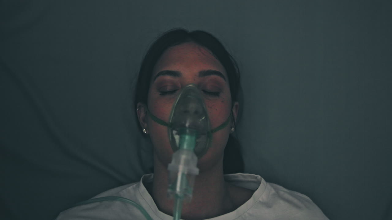 Woman wearing an oxygen mask in a hospital bed