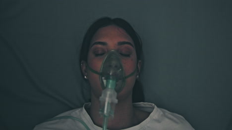 woman wearing an oxygen mask in a hospital bed