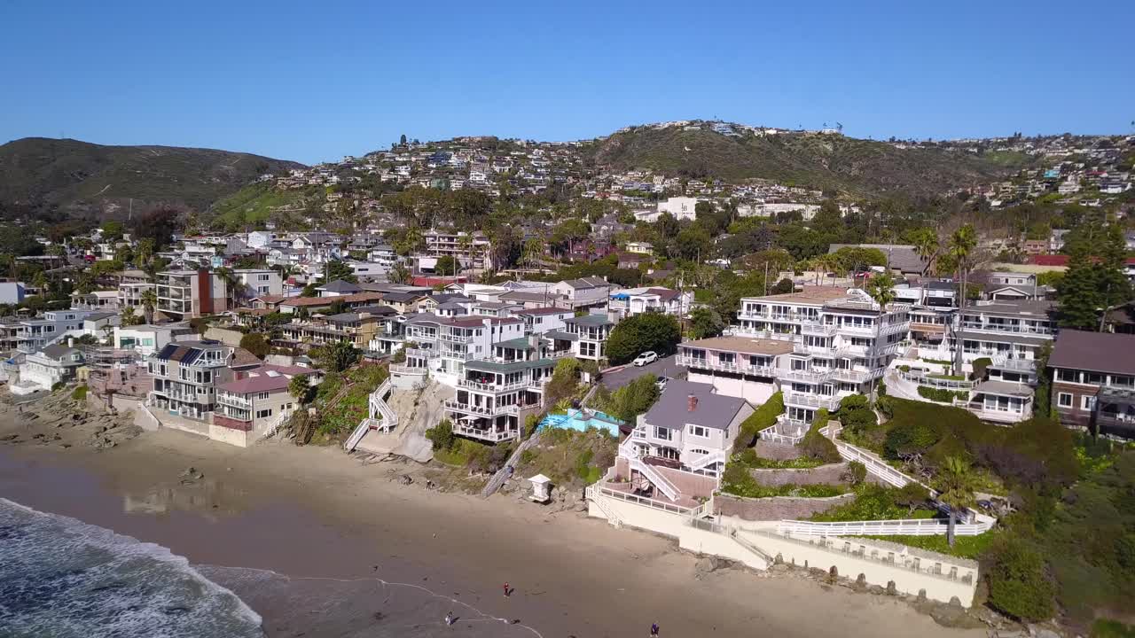 4k panorámica aérea de la playa de la laguna con el océano pacífico y enormes fincas frente a la playa en aguas cristalinas en un día soleado
