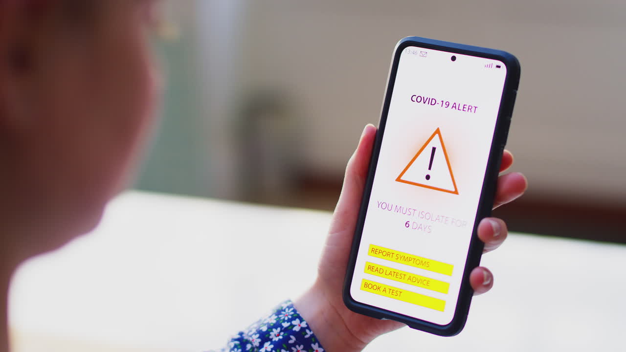 Close up of woman holding mobile with Covid 19 Track and Trace alert on screen - shot in slow motion