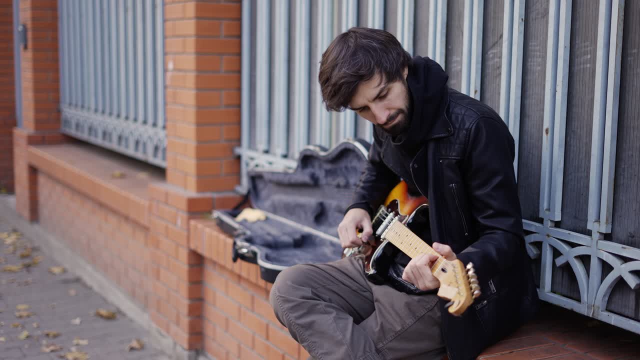 Guy playing on the giutar on the street with enthusiasm