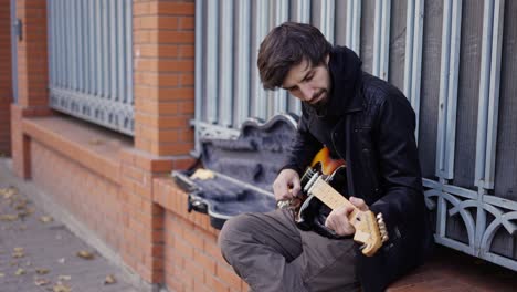 guy playing on the giutar on the street with enthusiasm