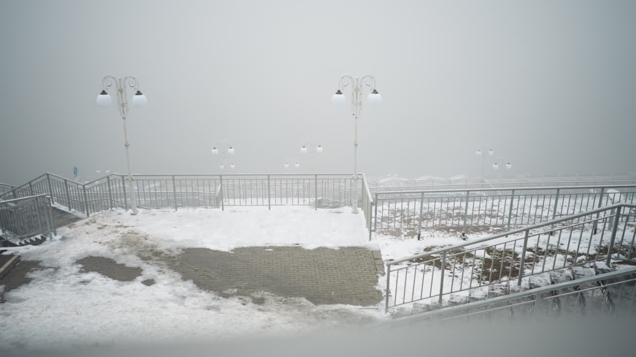 눈 인 계단과 플랫폼을 둘러싼 빛의 기둥과 눈으로 인 철의 레일링을 가진 안개가 은 분위기, 소음이 낮은 음색과 부드러운 조명은 조용하고 겨울의 도시 환경을 만니다.