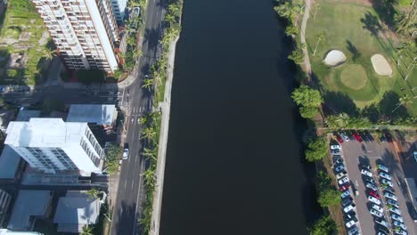 Aerial-tilt-up-of-Ala-Wai-Canal-revealing-city-of-Honolulu,-Hawaii