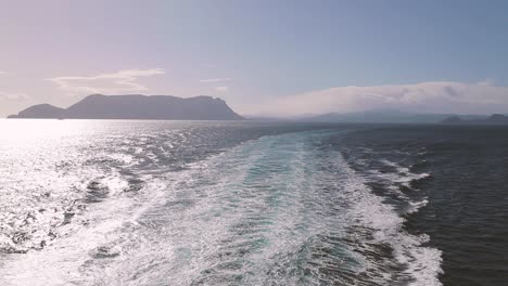 amplia toma de drones en cámara lenta para el océano con islas de montaña lejanas en el fondo