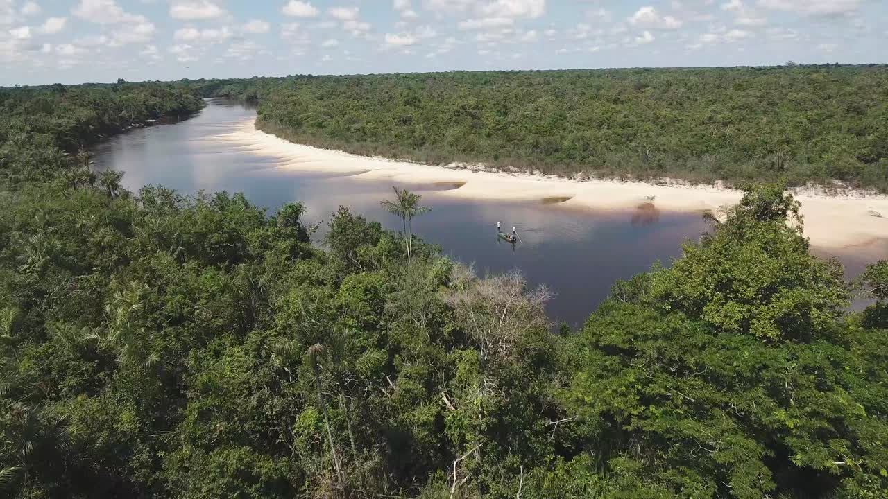 volando hacia dos pescadores que están pescando con mosca en medio de la selva tropical