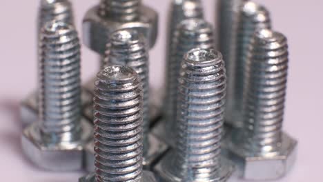 rotating group of galvanized metallic screws close-up. steinless steel bolts isolated on white background.