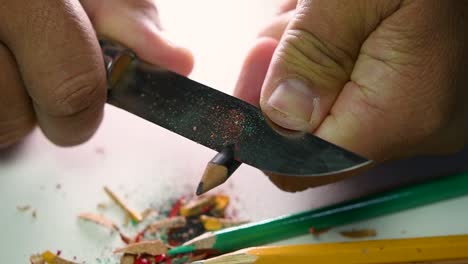 Footage-of-hands-slowly-sharpening-a-pencil-and-some-coloured-pencils-with-a-sharp-knife