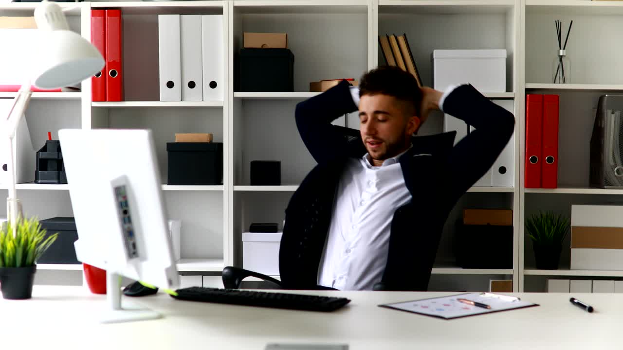 young businessman working on computer and leaning back in office-chair