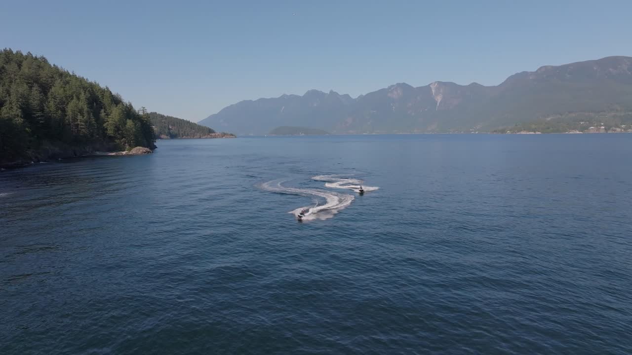 Moto d'acqua in una giornata di sole sull'oceano a Vancouver, in Canada. Cielo azzurro, due persone, acque calme e riprese effettuate con un drone.