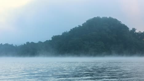 sunrise over a misty lake with moving fog