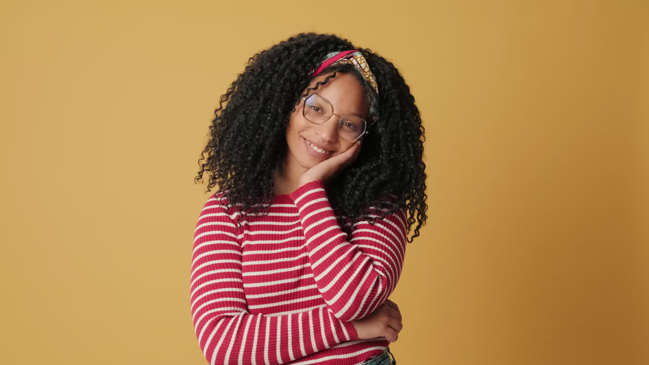 Happy Young Woman with Curly Hair and Glasses Smiling at Camera