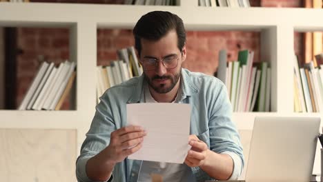 un joven curioso abriendo un sobre con correspondencia de negocios.