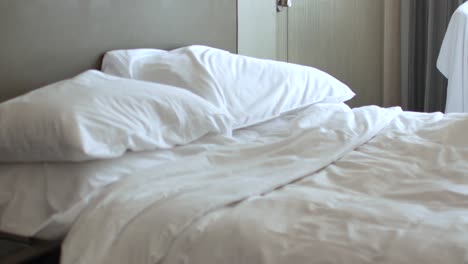 housekeeper is making the bed in the room- place pillow into the bed